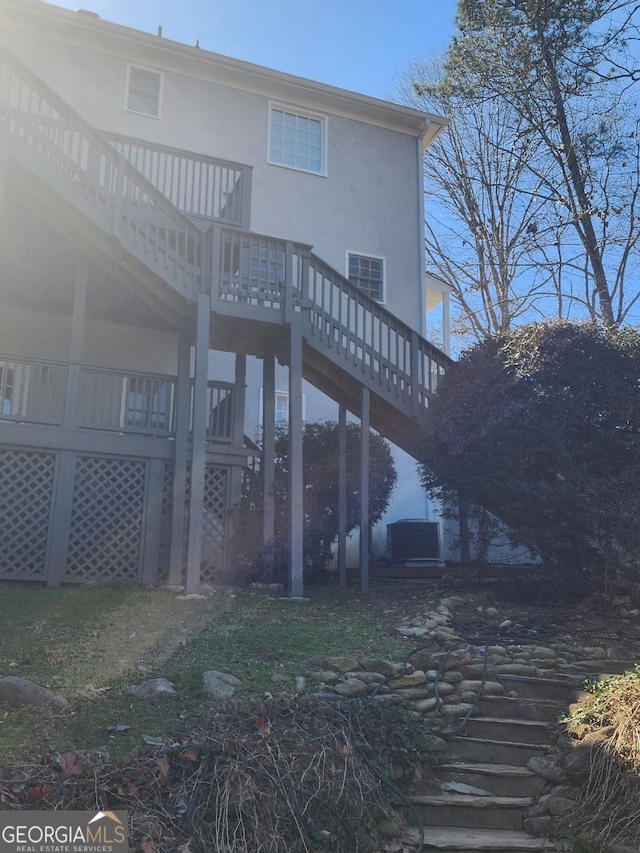 back of property featuring stucco siding, a deck, and stairs