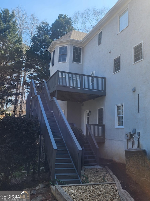 rear view of property with stucco siding and stairs