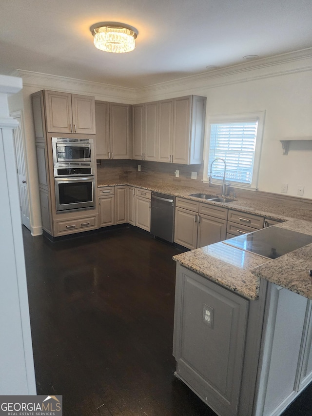 kitchen with light stone counters, dark wood-style flooring, a sink, ornamental molding, and appliances with stainless steel finishes