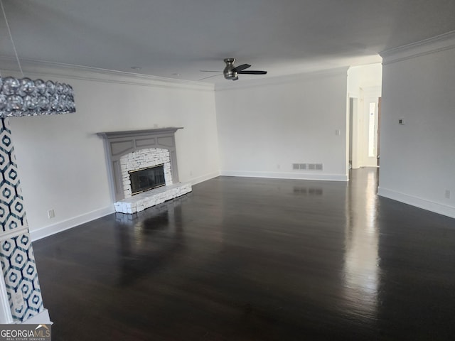 unfurnished living room featuring visible vents, dark wood-style floors, ceiling fan, ornamental molding, and a stone fireplace