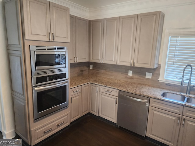 kitchen featuring decorative backsplash, dark wood-type flooring, light stone countertops, stainless steel appliances, and a sink