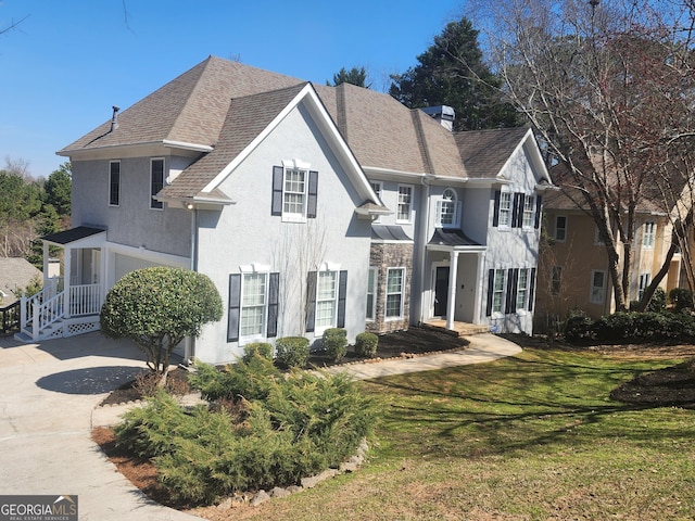 view of front of house featuring driveway, a shingled roof, a chimney, a front lawn, and stucco siding