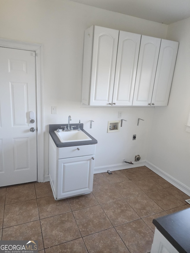 laundry area featuring hookup for a washing machine, hookup for an electric dryer, dark tile patterned flooring, a sink, and cabinet space