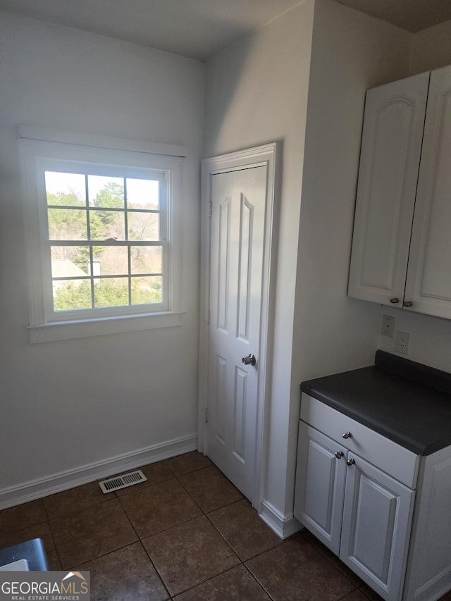 interior space with dark tile patterned flooring, visible vents, and baseboards