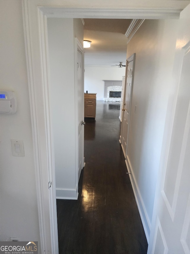 hallway featuring dark wood-style floors, baseboards, and ornamental molding