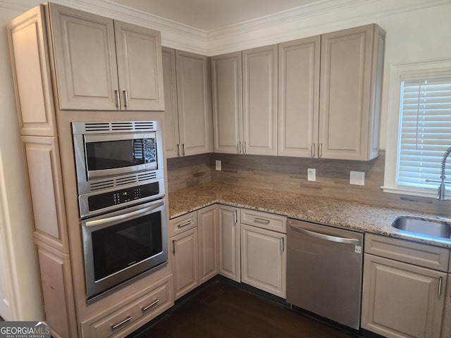 kitchen featuring light stone counters, a sink, appliances with stainless steel finishes, dark wood-style floors, and tasteful backsplash