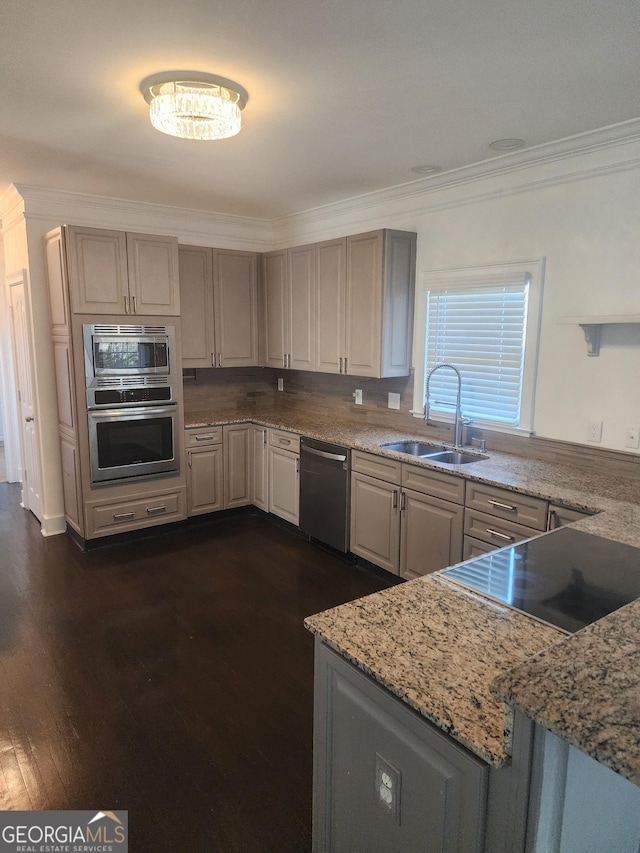 kitchen featuring light stone counters, dark wood-style floors, appliances with stainless steel finishes, ornamental molding, and a sink