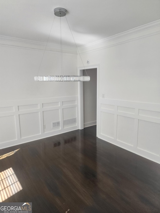 spare room featuring dark wood-style floors, visible vents, crown molding, and a decorative wall