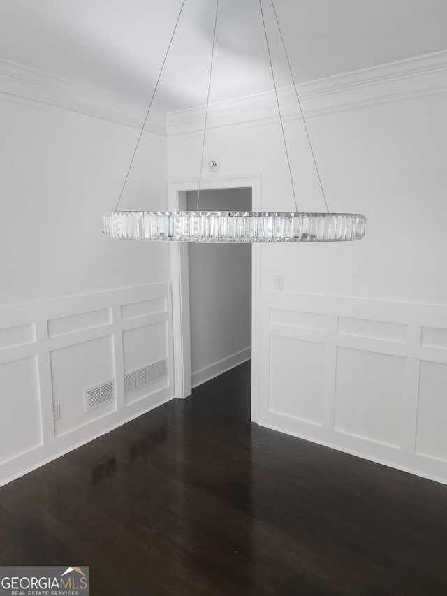 interior space with dark wood-type flooring, visible vents, a decorative wall, and crown molding