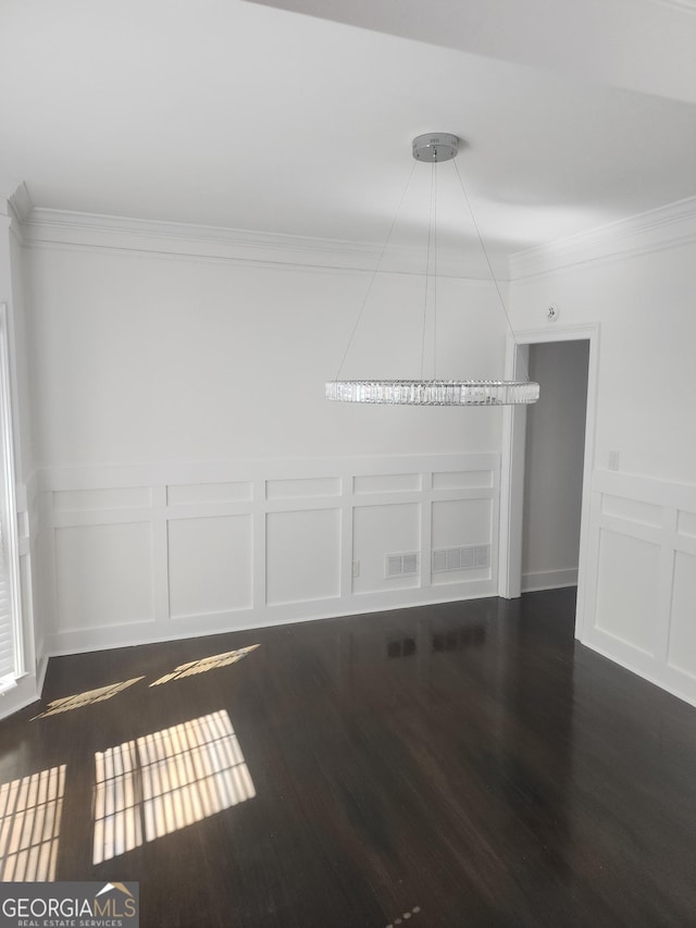 empty room with ornamental molding, dark wood finished floors, visible vents, and a decorative wall