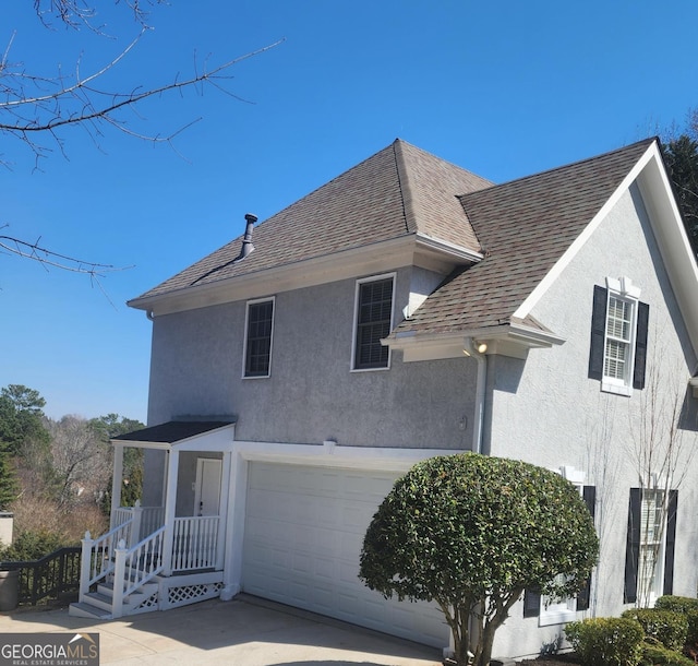 view of front of house with a garage, a shingled roof, and stucco siding