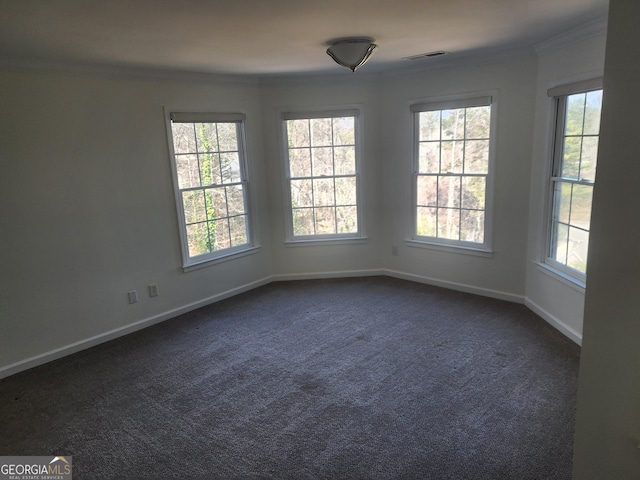 empty room featuring ornamental molding, dark carpet, visible vents, and baseboards