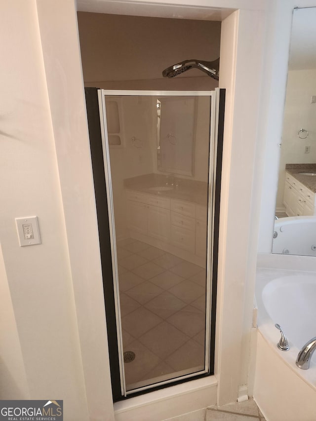 bathroom with a stall shower, vanity, and a bath