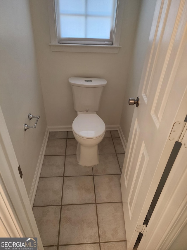 bathroom with toilet, baseboards, and tile patterned floors