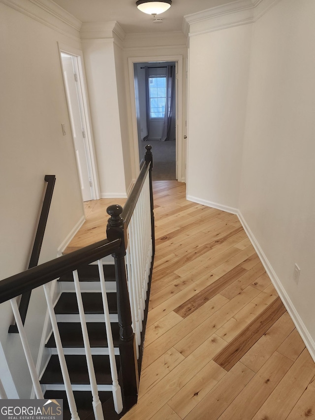 hall with crown molding, baseboards, an upstairs landing, and light wood-style floors