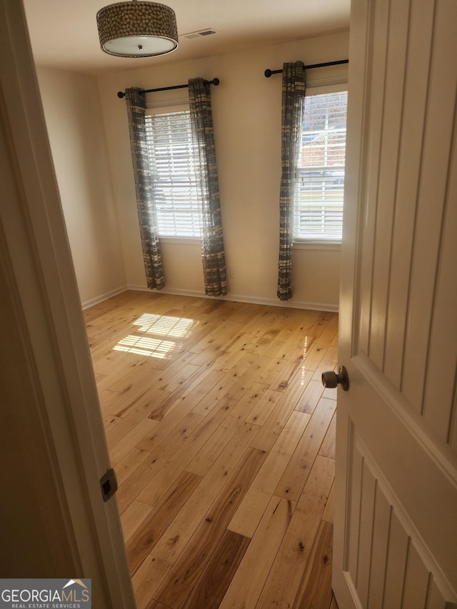 spare room with visible vents, baseboards, and hardwood / wood-style flooring