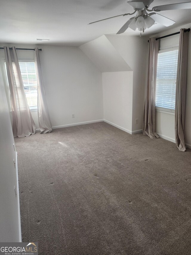 additional living space with carpet flooring, vaulted ceiling, baseboards, and ceiling fan