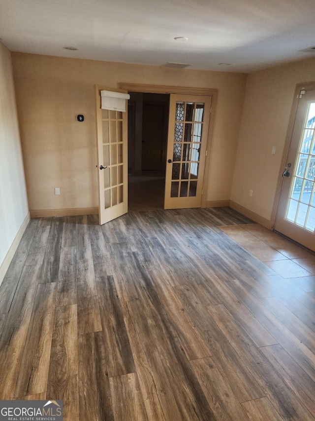 spare room with french doors, wood finished floors, visible vents, and baseboards