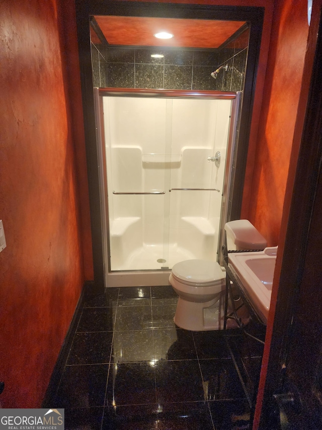 full bath with toilet, granite finish floor, a sink, baseboards, and a stall shower