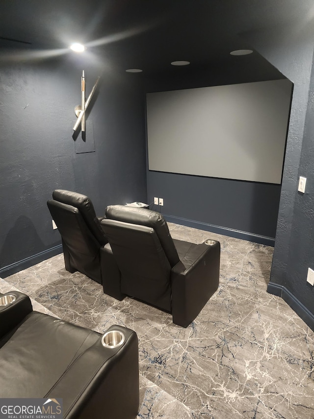 cinema room with stone finish floor, a textured wall, and baseboards