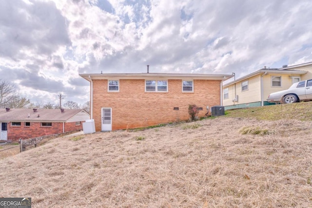 rear view of property with central AC unit, crawl space, fence, and brick siding