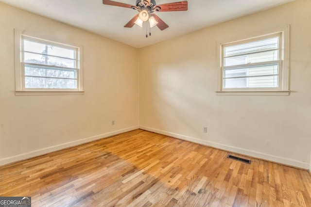 unfurnished room featuring a healthy amount of sunlight, baseboards, visible vents, and wood finished floors