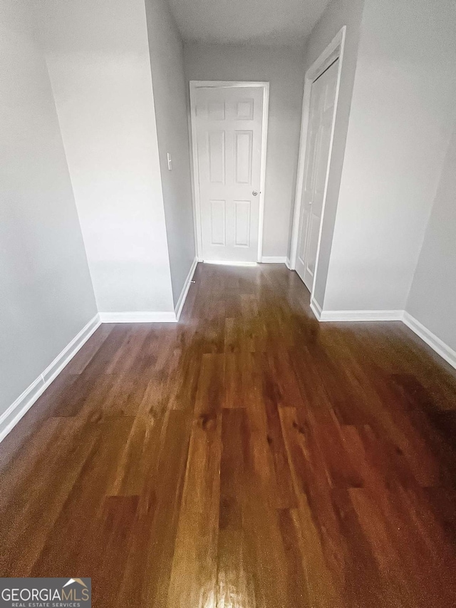 corridor featuring wood finished floors and baseboards