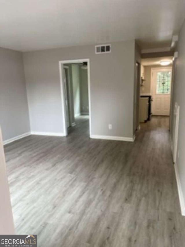 empty room featuring baseboards, visible vents, and wood finished floors