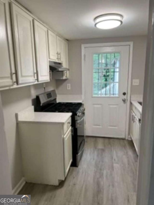 kitchen with light countertops, stainless steel gas range oven, light wood-style flooring, and under cabinet range hood