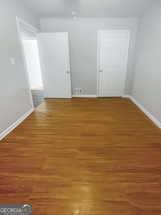 unfurnished room featuring visible vents, light wood-style flooring, and baseboards