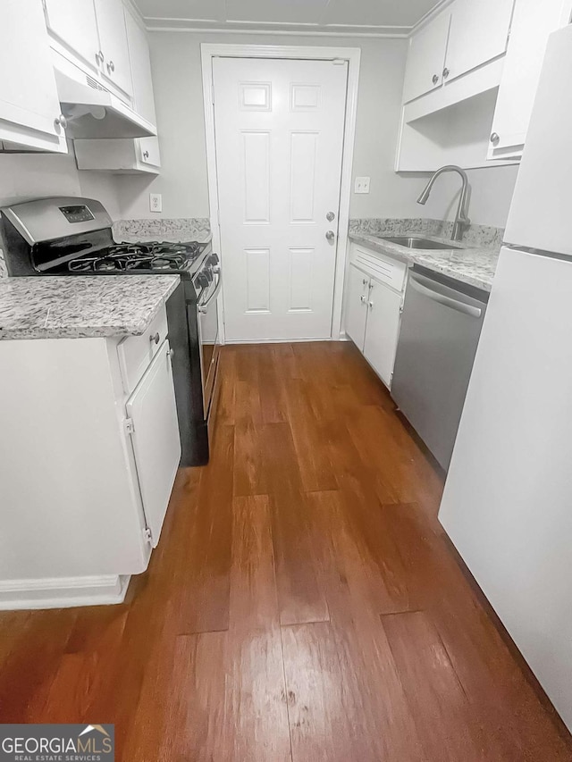 kitchen with under cabinet range hood, stainless steel appliances, a sink, white cabinetry, and dark wood-style floors