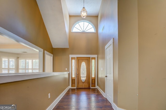 foyer entrance featuring visible vents, dark wood finished floors, a towering ceiling, and baseboards