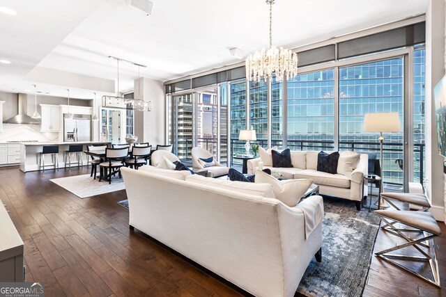 living area with dark wood-style floors, floor to ceiling windows, rail lighting, and an inviting chandelier