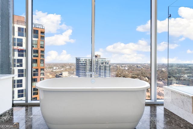 bathroom featuring a soaking tub, a view of city, and marble finish floor