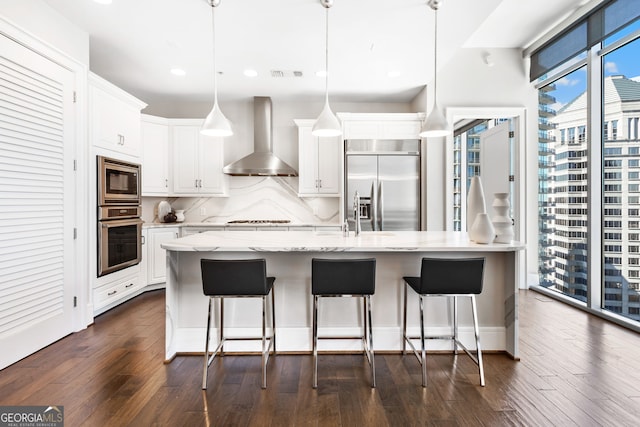 kitchen with backsplash, dark wood-style floors, wall chimney exhaust hood, white cabinets, and built in appliances