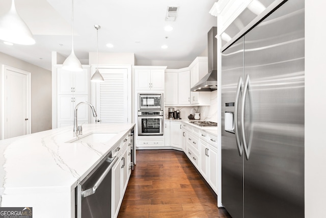 kitchen featuring dark wood-style floors, a sink, white cabinets, appliances with stainless steel finishes, and wall chimney exhaust hood