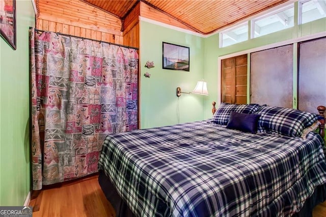 bedroom with lofted ceiling, wooden ceiling, wood finished floors, crown molding, and a closet