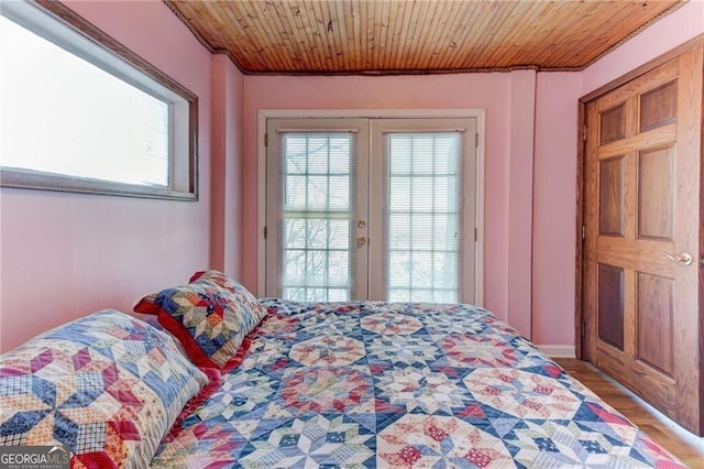 bedroom with access to outside, french doors, light wood-type flooring, and wooden ceiling