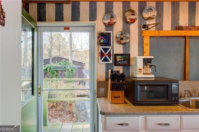 interior space featuring white cabinetry, black microwave, and a sink