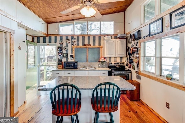 kitchen with stainless steel range with electric stovetop, wooden ceiling, black microwave, and light wood-style flooring