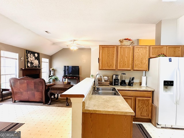 kitchen featuring lofted ceiling, light countertops, a sink, white fridge with ice dispenser, and a peninsula