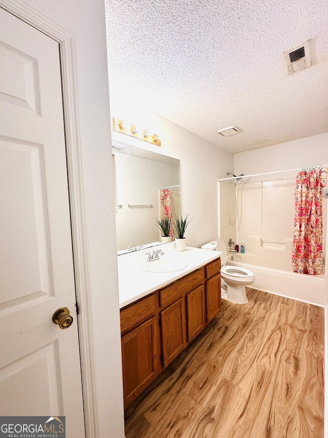 bathroom featuring a textured ceiling, toilet, wood finished floors, vanity, and visible vents