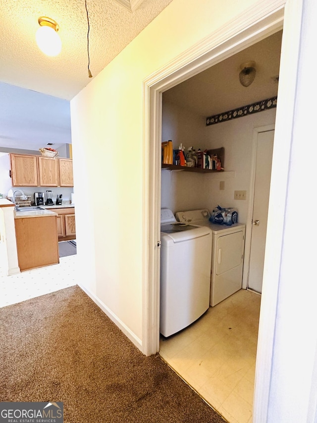 washroom with laundry area, washing machine and dryer, light floors, and a textured ceiling