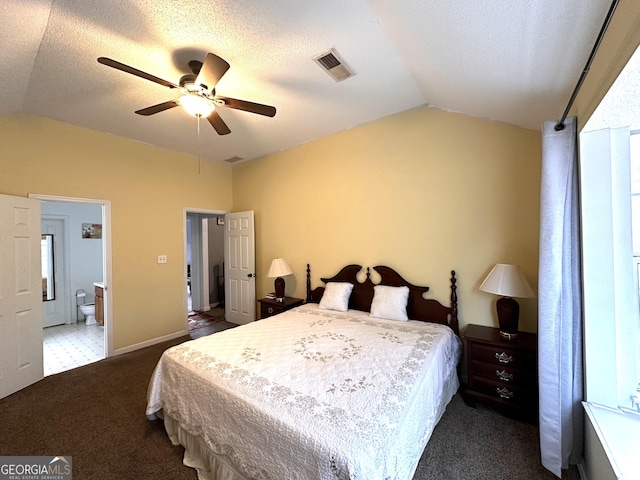 bedroom with dark colored carpet, visible vents, vaulted ceiling, a textured ceiling, and ensuite bath