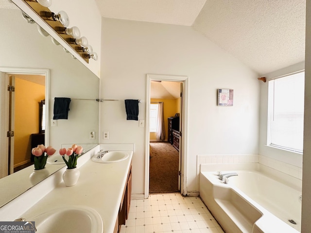 bathroom featuring double vanity, lofted ceiling, tile patterned floors, a sink, and a bath