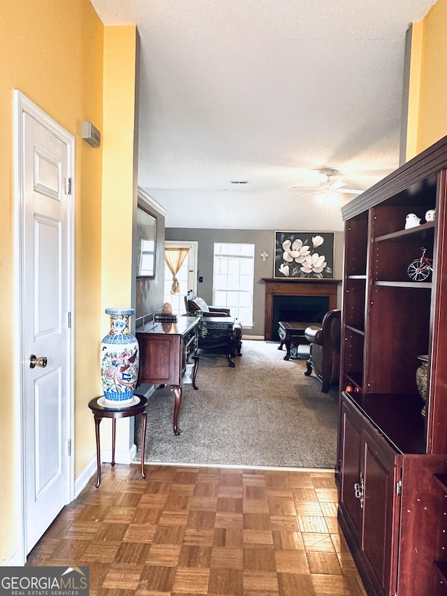 office area with ceiling fan, a textured ceiling, a fireplace, and baseboards