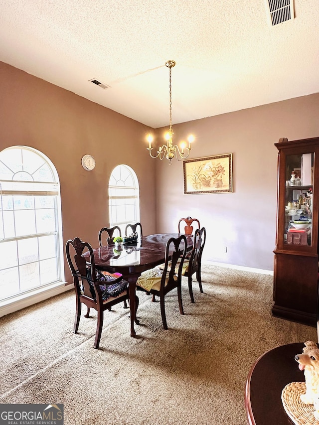 dining space with a textured ceiling, visible vents, a chandelier, and carpet flooring