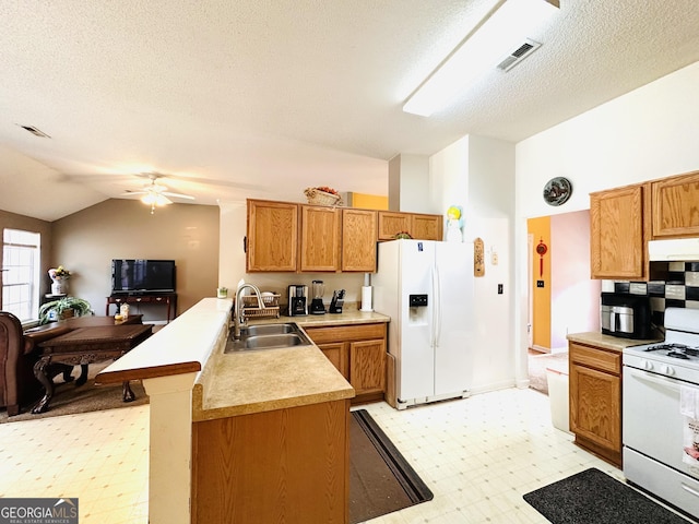 kitchen with white appliances, lofted ceiling, a peninsula, light floors, and a sink