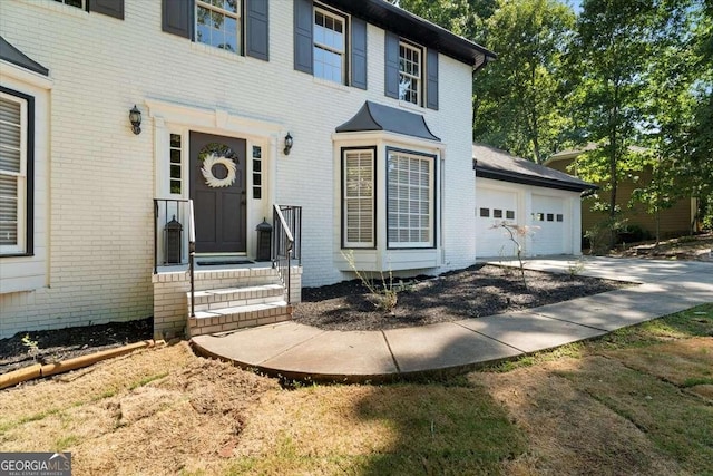 entrance to property featuring concrete driveway, brick siding, and an attached garage