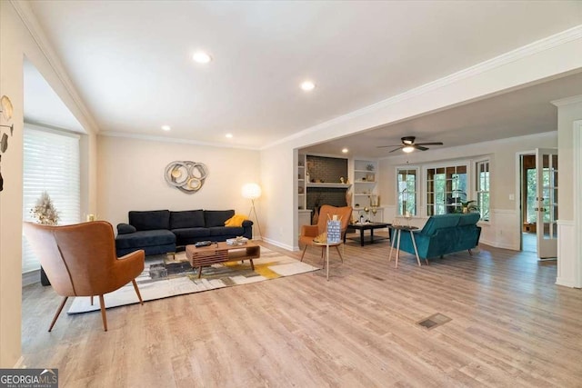 living area with built in features, crown molding, a fireplace, visible vents, and wood finished floors